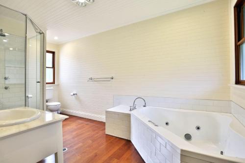 a white bathroom with a tub and a sink at The Cottage - By Berry Getaways in Berry