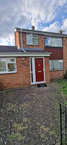a red brick house with a red door at Serene Inn Near Bletchley Park in Bletchley