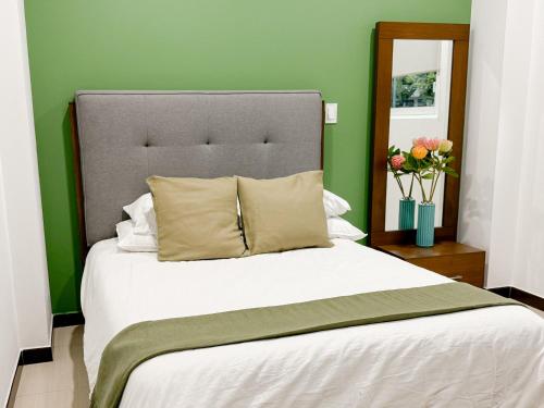 a bedroom with a large white bed with a green wall at Acogedor y hermoso cerca del Foro Sol, AICM y Coyoacán in Mexico City