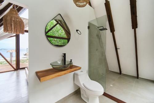 a bathroom with a toilet and a mirror at El Embrujo Tintipan in Tintipan Island