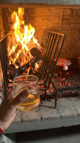 a person holding a glass of water in front of a fireplace at Casitas Atlántida in Atlántida