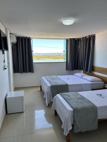 a hotel room with two beds and a window at Hotel Beira do Rio in Ibotirama