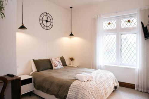 a bedroom with a bed and a clock on the wall at Harmony House - CBD in Launceston