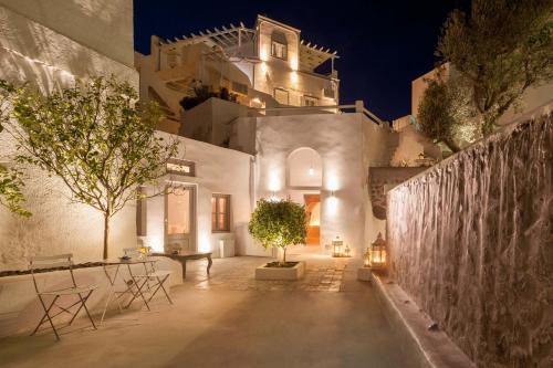 a white building with a tree in a courtyard at night at Senses Boutique Hotel in Imerovigli