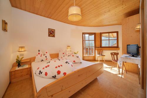 Dormitorio con cama, escritorio y TV en Gasthof Meierei, en Carezza al Lago