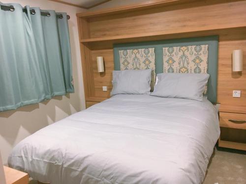 a bedroom with a large white bed with a blue headboard at Carlisle CAMELOT HOLIDAY PARK CA65SZ Blenheim in Longtown