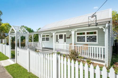 a white picket fence in front of a white house at Rosemill Cottage - By Berry Getaways in Berry