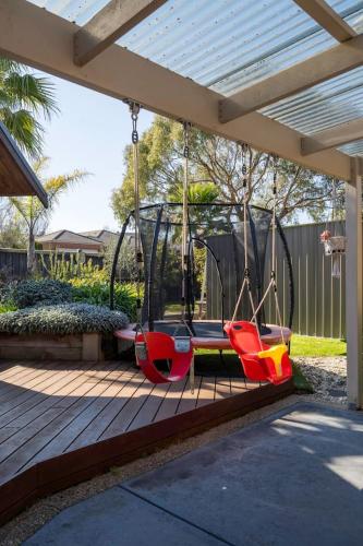 a swing set on a deck in a backyard at Endless Entertainment on the Coast - A Family Oasis in Mornington
