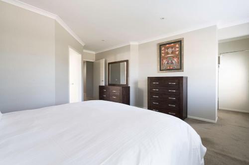 a white bedroom with a large bed and a dresser at Endless Entertainment on the Coast - A Family Oasis in Mornington