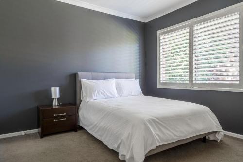 a bedroom with a white bed and a window at Endless Entertainment on the Coast - A Family Oasis in Mornington