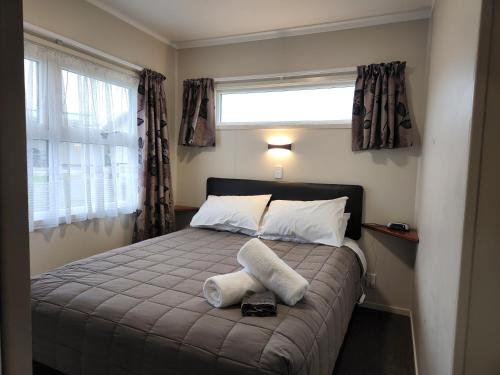 a bedroom with a bed with two towels on it at Hīmatangi Beach TOP 10 Holiday Park in Oroua Downs