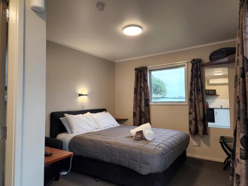 a hotel room with a bed and a window at Hīmatangi Beach TOP 10 Holiday Park in Oroua Downs