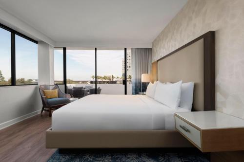 a bedroom with a large white bed and windows at Renaissance Newport Beach Hotel in Newport Beach