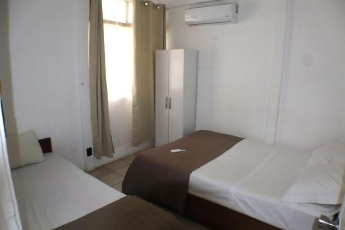 a small room with two beds and a window at Coconut Beach House in Playa Conchal