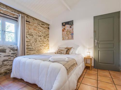 une chambre avec un lit blanc et un mur de briques dans l'établissement Maison avec piscine privée chauffée, proche plage à Pornic - FR-1-306-1284, à Pornic