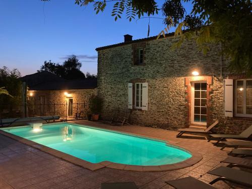 - une piscine en face d'une maison en pierre la nuit dans l'établissement Maison avec piscine privée chauffée, proche plage à Pornic - FR-1-306-1284, à Pornic