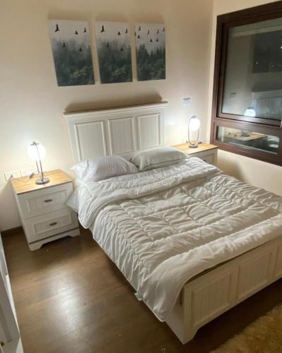 a bedroom with a large white bed with two night stands at شقه فندقيه بيفرلي هيلز كومبوند one16 in Sheikh Zayed