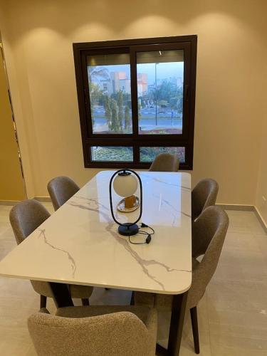 a table in a room with chairs and a window at شقه فندقيه بيفرلي هيلز كومبوند one16 in Sheikh Zayed