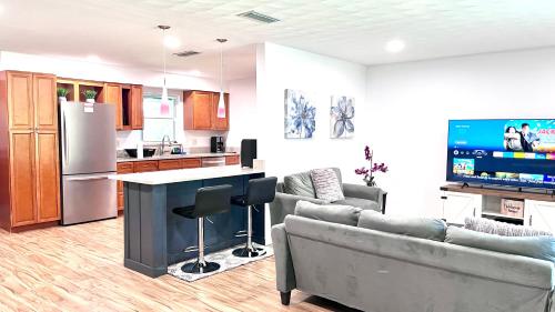 a kitchen and living room with two couches and a tv at LuxCoral - 4 Min walk to beach! in Cape Canaveral