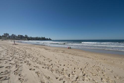 a beach with footprints in the sand and the ocean at Oceanfront Views at Rolling Surf Resort in Caloundra