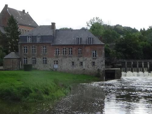 un vieux bâtiment en brique à côté d'une masse d'eau dans l'établissement Gîte de charme à Leval, 4 chambres, cheminée, cour privative, proche nature et randonnées - FR-1-510-175, à Leval