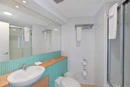 Un baño con lavabo, inodoro y ducha. en The Entrance Waterfront Apartment 302, en The Entrance