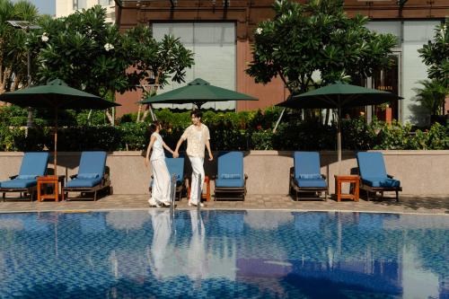 a man and woman standing next to a swimming pool at DLG Hotel Danang in Da Nang