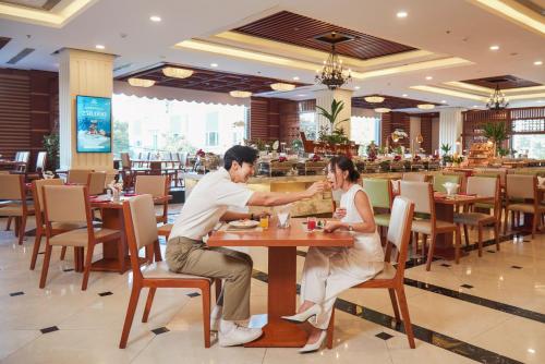 a man and woman sitting at a table in a restaurant at DLG Hotel Danang in Da Nang
