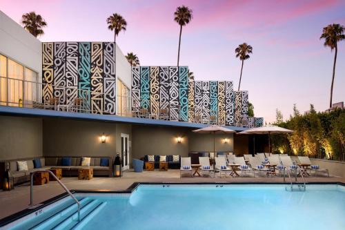 a resort with a pool and a building with palm trees at Hyatt Centric Delfina Santa Monica in Los Angeles