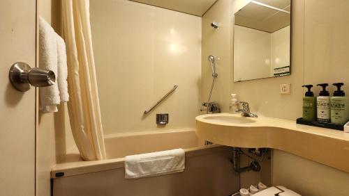 bagno con lavandino, vasca e specchio di Platon Hotel Yokkaichi a Yokkaichi