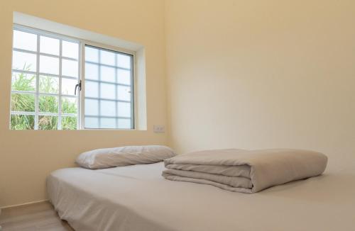 a bedroom with a bed with white sheets and a window at Ocean Diary Hostel in Green Island