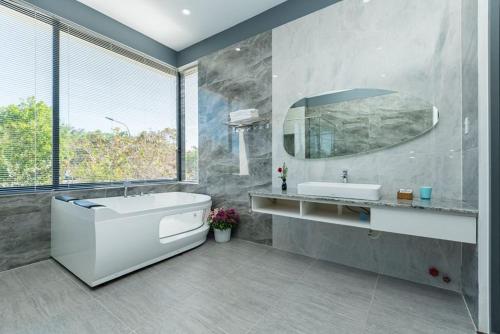 ein Badezimmer mit Badewanne, Waschbecken und Spiegel in der Unterkunft Villa 50M To Beach - Room Karaoke Free in Vũng Tàu