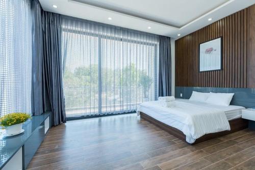 ein Schlafzimmer mit großem Bett und großen Fenstern in der Unterkunft Villa 50M To Beach - Room Karaoke Free in Vũng Tàu