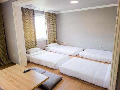a room with three beds and a table at La Vie Dor Hotel and Resort, Trademark Collection by Wyndham in Hwaseong