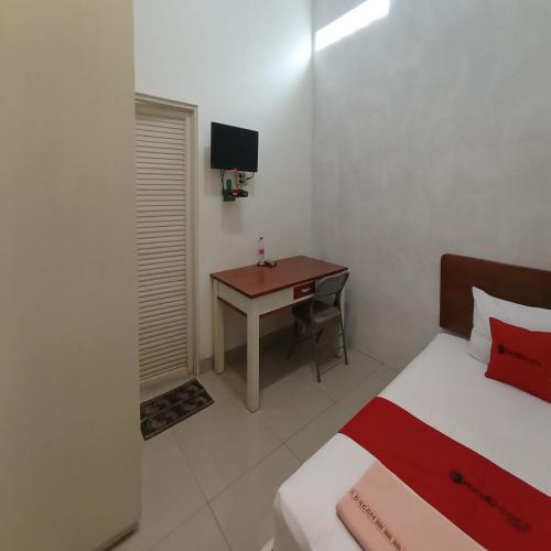 a bedroom with a bed and a desk with a computer at RedDoorz at Syariah House Purwokerto in Purwokerto
