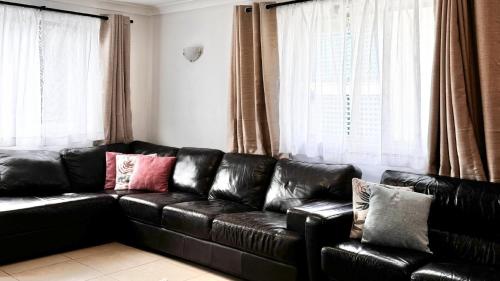 a black leather couch in a living room with windows at The Perch in Yamba