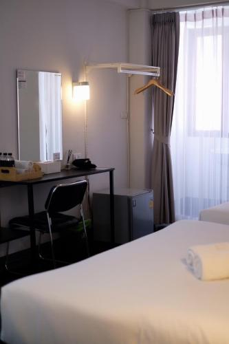 a bedroom with a bed and a desk and a window at Shane Hotel in Chiang Mai