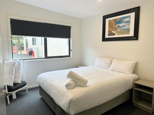 a bedroom with a large white bed with a window at Eastcoaster Tasmania in Orford