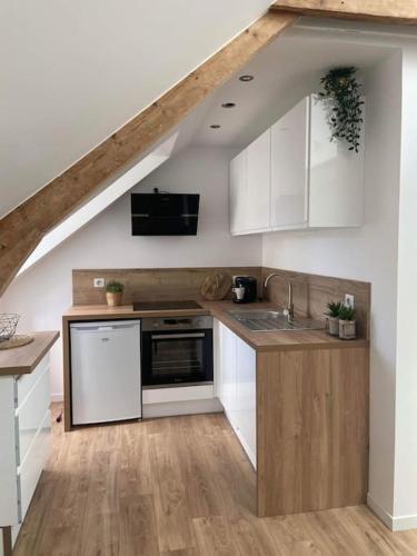 - une cuisine mansardée avec des placards blancs et un évier dans l'établissement Le Patio, Hyper centre rue au calme avec parking, à Cherbourg en Cotentin