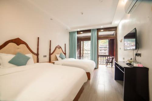 a hotel room with two beds and a television at Fenghuang Ancient Town Lazy Cat Riverside Inn in Fenghuang