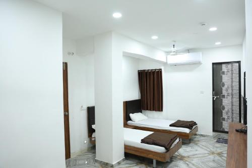 two beds in a room with white walls at Hotel Aaram Kalupur in Ahmedabad