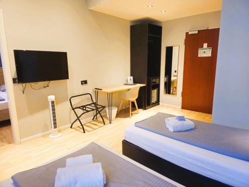 a room with two beds and a desk with a television at Novitel Hotel Kirchheim - München Messe in Kirchheim