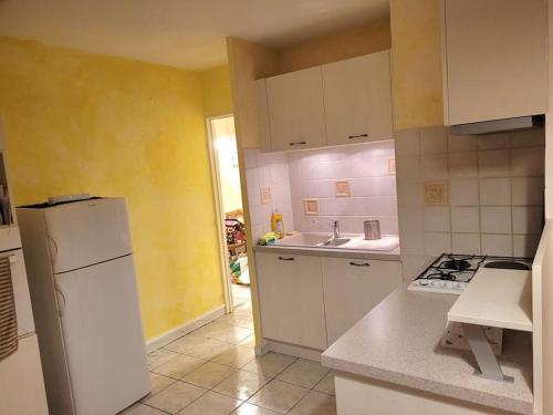 une cuisine avec des armoires blanches et un réfrigérateur blanc dans l'établissement Appartement T2 terrasse centre-ville, à Digne-Les-Bains