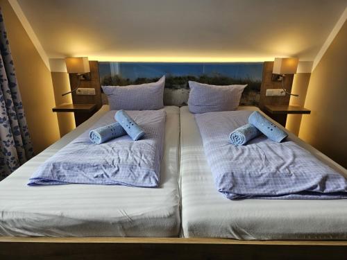 a large bed with white sheets and blue pillows at Hotel Pension Am Hafen in Norddeich
