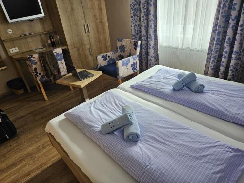 a bedroom with two beds and a chair and a laptop at Hotel Pension Am Hafen in Norddeich
