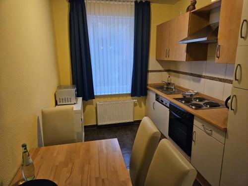 a small kitchen with a table and a refrigerator at Hotel Pension Am Hafen in Norddeich