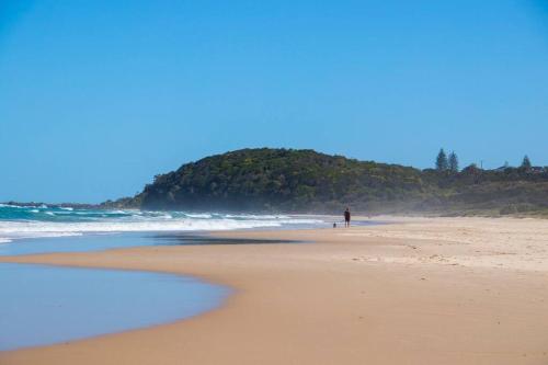 a person walking a dog on the beach at Ballina Beachside Retreat 3 min Walk onto Beach in East Ballina
