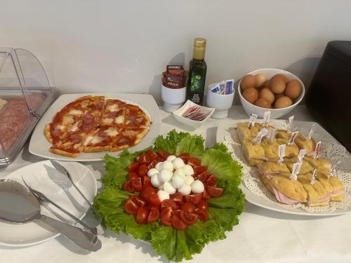 a table topped with plates of food and a pizza at Global Hotel in Rimini