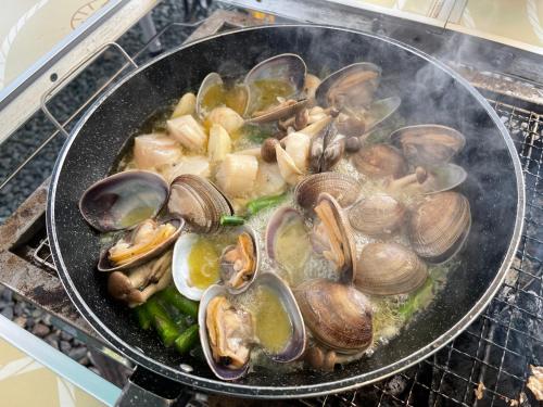 a pan filled withcooked clams and mushrooms on a stove at オホーツクの海の幸が食べられる 漁師の家ゲストハウスOhana in Abashiri