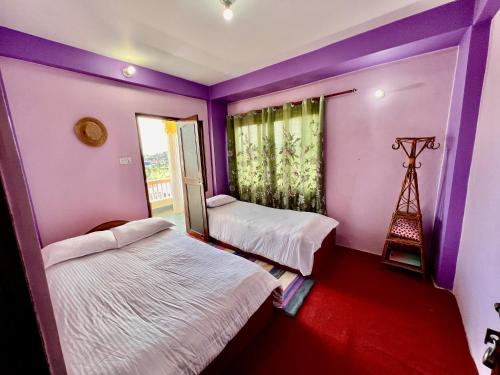 two beds in a room with purple walls and a window at Kathmandu Valley View Homestay in Kathmandu